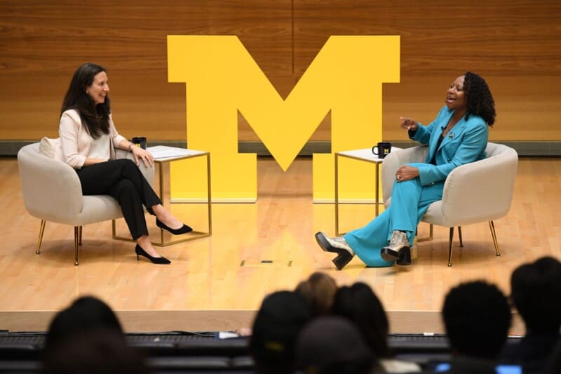 A stage in the Ross building with a yellow "M" logo in the background and two women speaking in a panel.